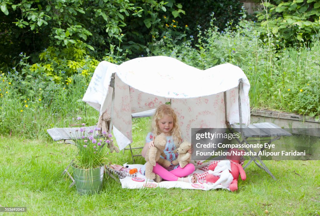 Girl playing in garden with teddy bears