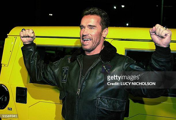 Austrian-born US actor Arnold Schwarzenegger poses by his yellow Hummer car as he arrives at the premiere of his new film "The 6th Day" in Los...