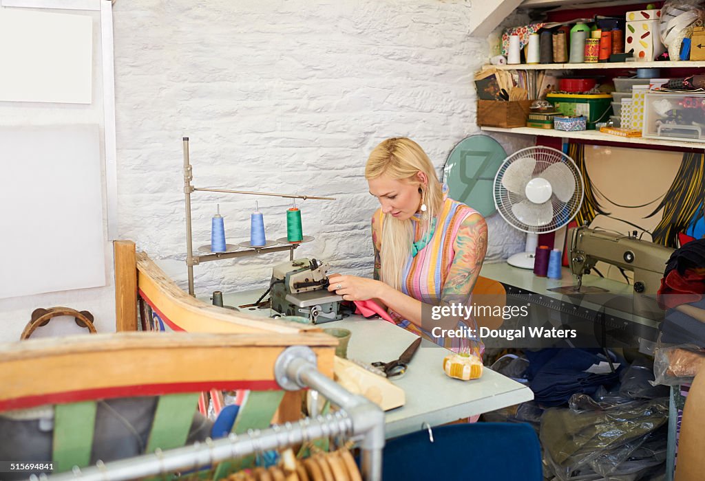 Woman sewing in vintage clothes shop.