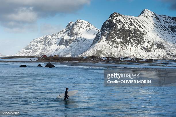Girl goes out the water at the snowy beach of Flackstad, in Lofoten archipelago, Arctic Circle, on March 13, 2016 Surfers from all over the world...