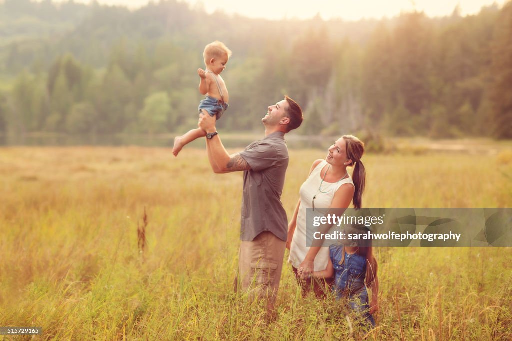 Family of four standing in a sunny meadow