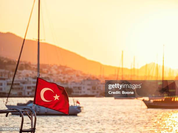 turkish flag waving in the wind in bodrum harbor - bodrum turkey stock pictures, royalty-free photos & images