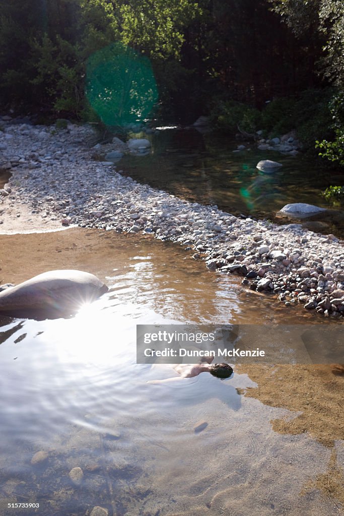 Man lying very still face down in a rock pool