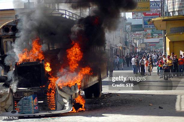 Habitantes de San Juan Sacatepeuez, 30 km de Ciudad de Guatemala, observan el 26 de octubre de 2004 un autobus consumiendose por las llamas. Dos...