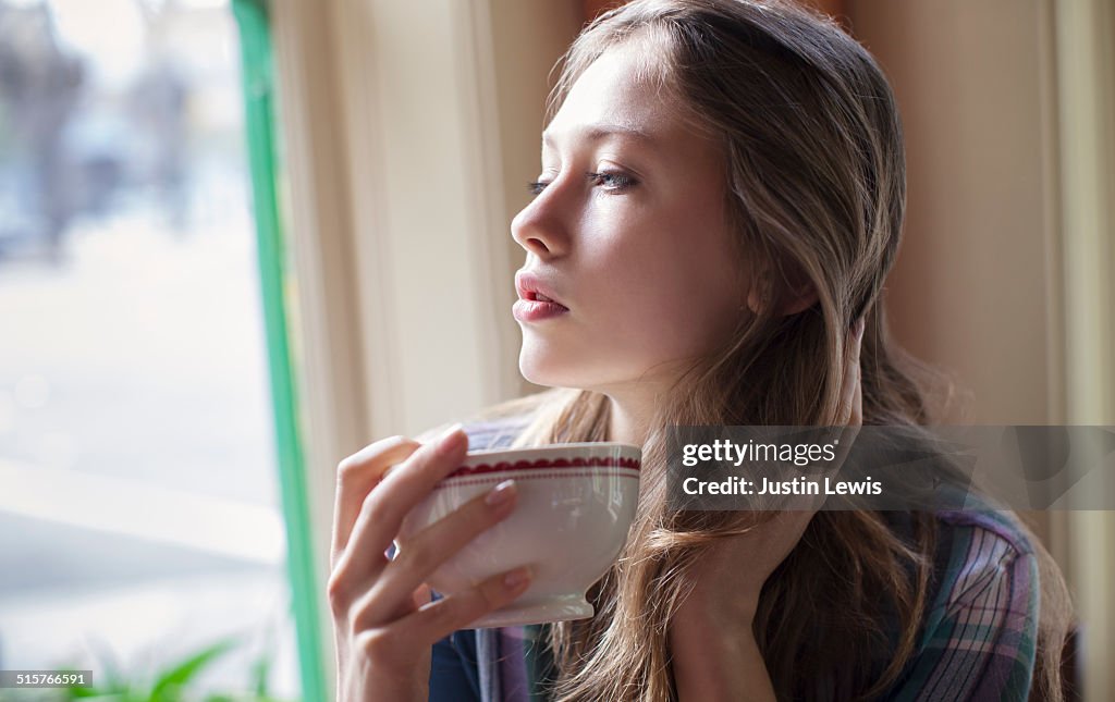 Girl in cafe drinking tea and thinking