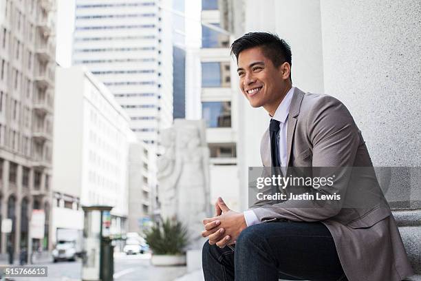 young asian businessman in city smiling - chinese businessman stock-fotos und bilder