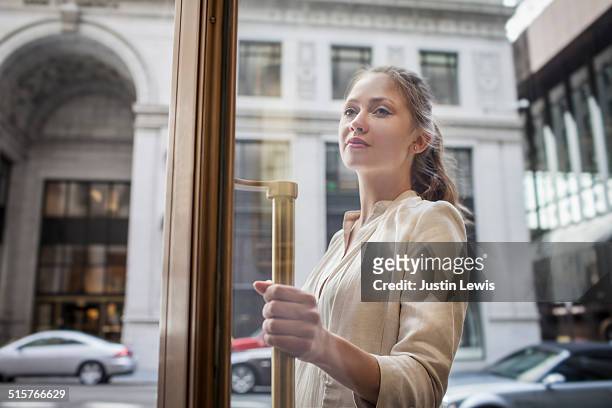 young business woman entering building - entrando fotografías e imágenes de stock