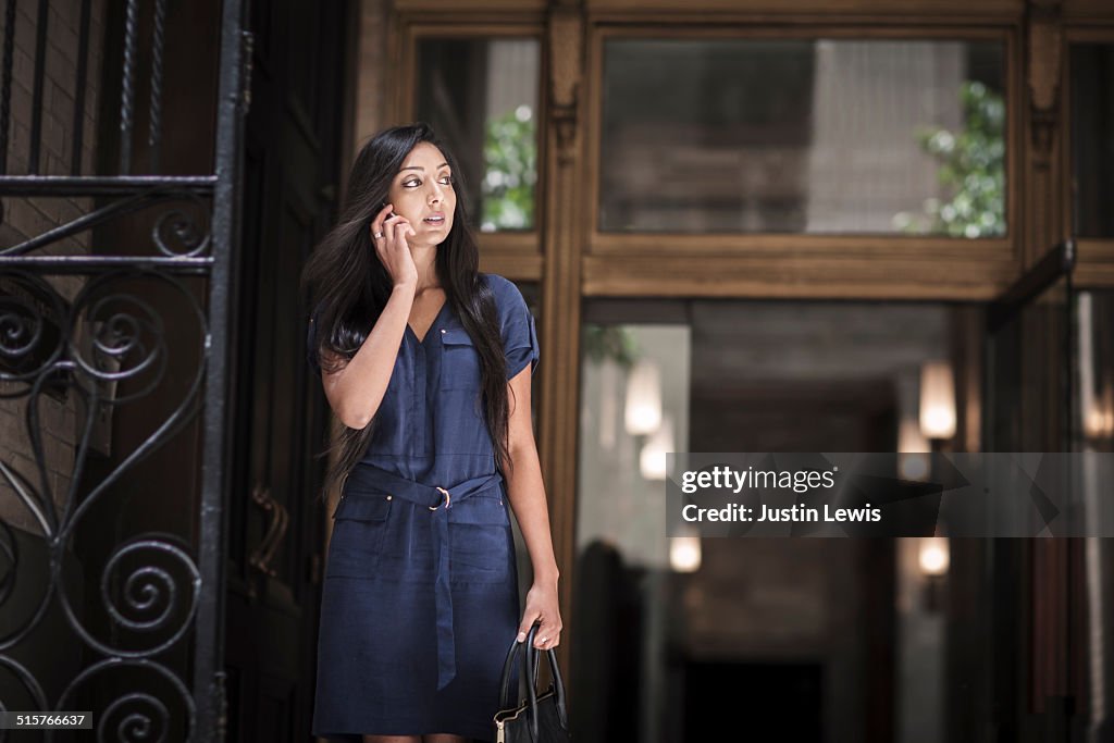 Young Asian woman on phone, city doorway