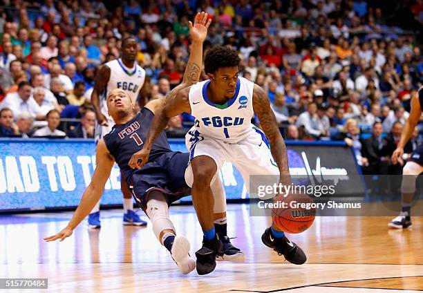 Stephan Jiggetts of the Fairleigh Dickinson Knights falls as Reggie Reid of the Florida Gulf Coast Eagles handles the ball in the second half of...