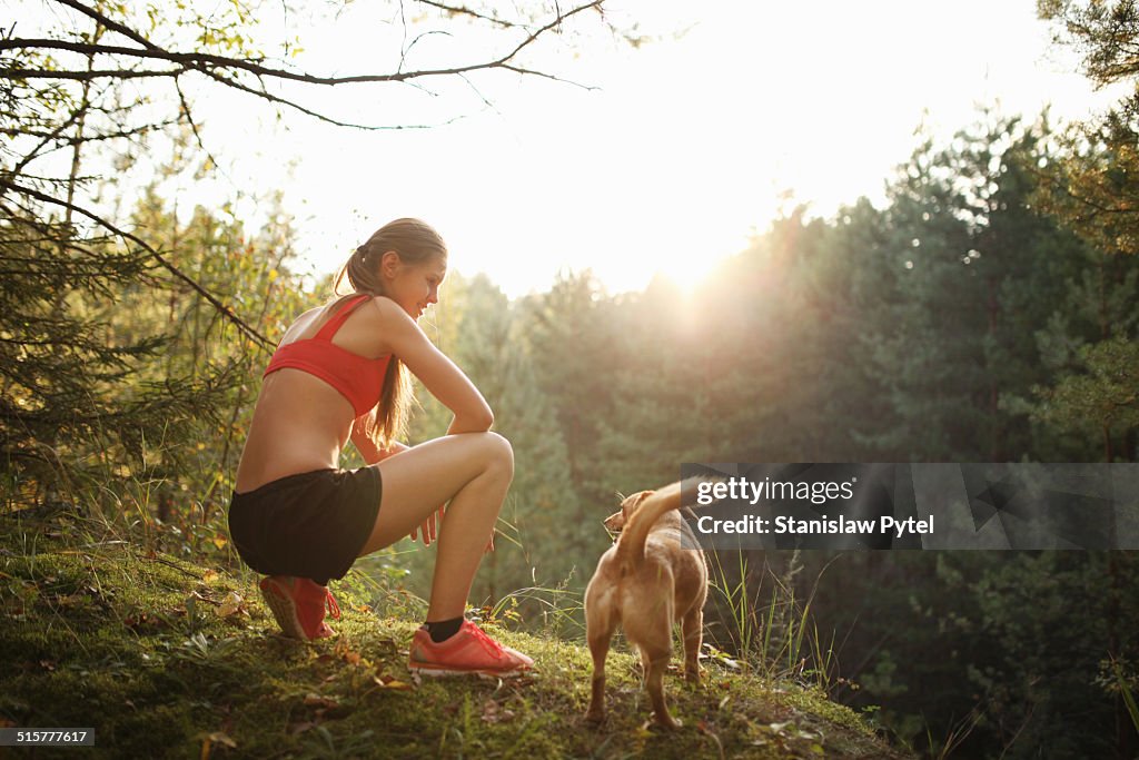 Runner with her dog at scenic overlook in forest