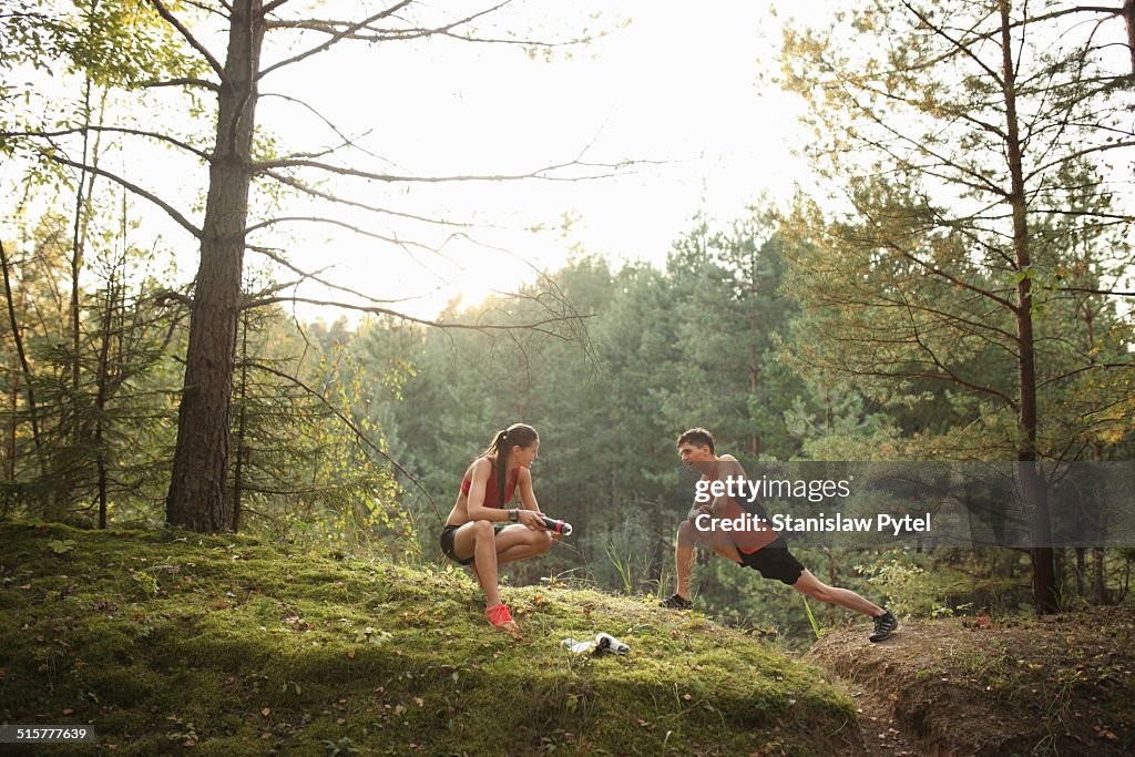 Two runners stretching before run in forest