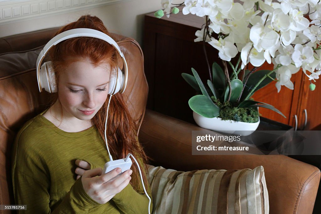 Image of teenage girl listening to music on large headphones