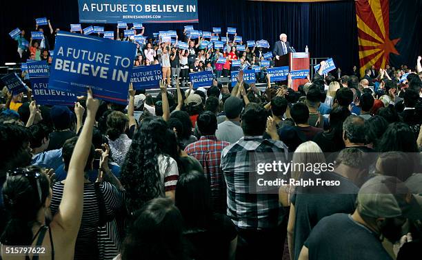 Supporters hold up signs as Democratic presidential candidate Sen. Bernie Sanders speaks at the Phoenix Convention Center during a campaign rally on...