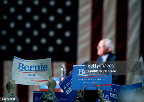 Supporters hold up signs as Democratic presidential candidate Sen. Bernie Sanders speaks at the Phoenix Convention Center during a campaign rally on...