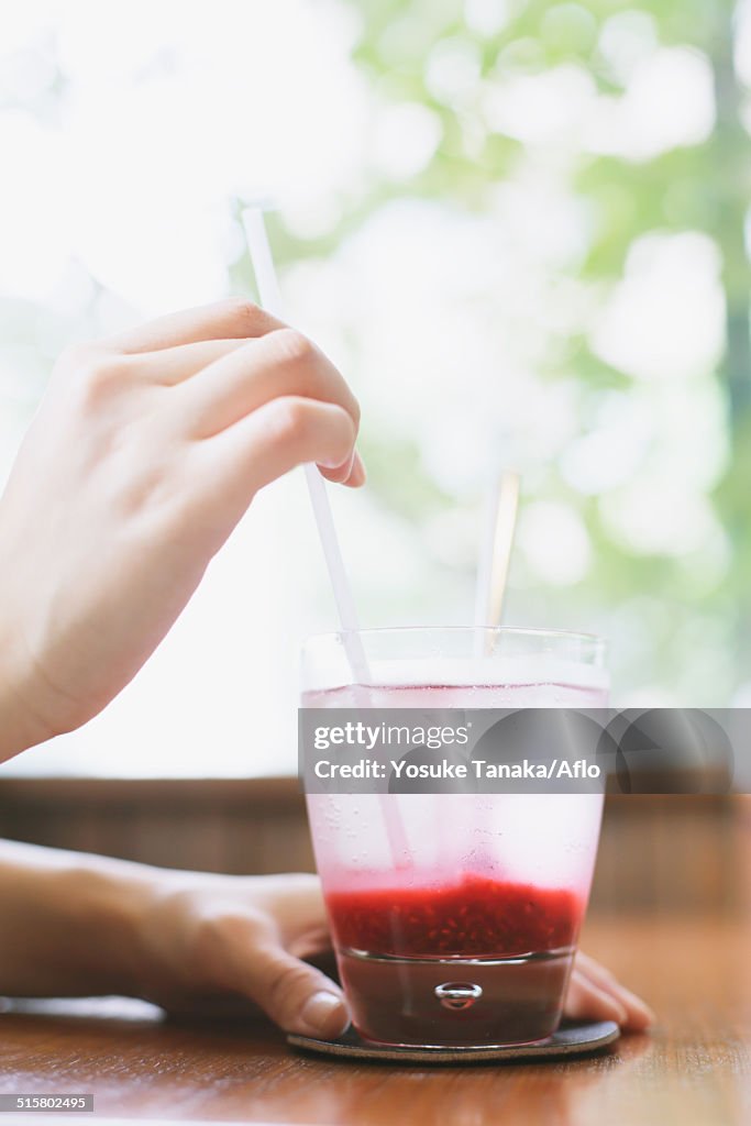 Young Japanese woman with raspberry soda in a cafe