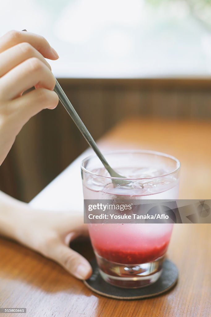 Young Japanese woman with raspberry soda in a cafe