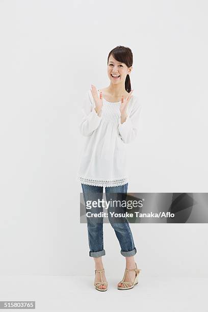 japanese young woman in jeans and white shirt standing against white background - clapping hands on white stock pictures, royalty-free photos & images