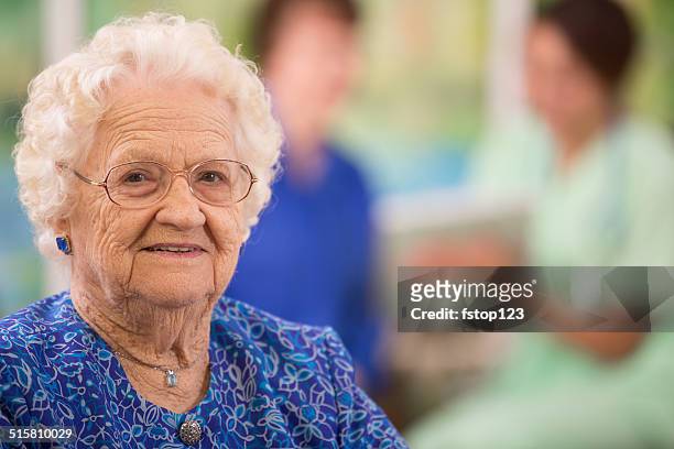 elderly woman patient foreground. nurse, daughter. nursing home. - volunteer aged care stock pictures, royalty-free photos & images