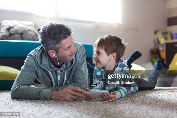 father and son listening music - sharing headphones stock pictures, royalty-free photos & images