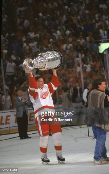 Canadian professional hockey player defenseman Larry Murphy of the Detroit Red Wings hoists the Stanley Cup over his head after they complete a sweep...