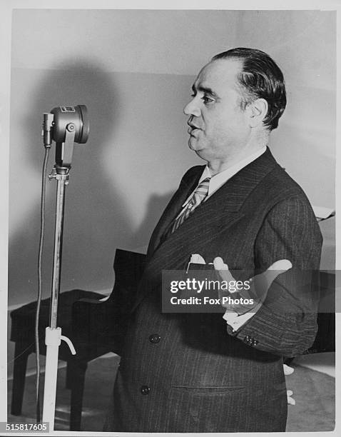 Italian opera tenor Beniamino Gigli singing into a microphone in a recording studio, during a visit to HMV's new West End showroom, London, circa...