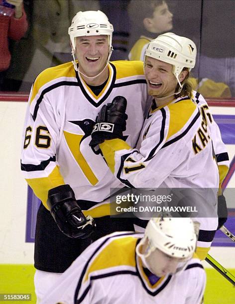 Pittsburgh Penguins owner and player Mario Lemieux celebrates with teammate Darius Kasparaitis after Lemieux scored his first goal since returning as...