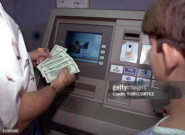 Man with his daughter makes a withdrawl of cash from his savings account at an automatic teller machine, 01 January in San Salvador, El Salvador. Afp...