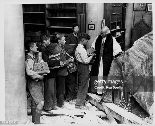 Reverend Dr Hewlett Johnson, Dean of Canterbury Cathedral, instructing boys to salvage books from the damaged Cathedral Library, June 29th 1942.