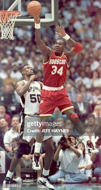 Hakeem Olajuwon of the Houston Rockets grabs a pass as David Robinson of the San Antonio Spurs guards 22 May during the first half of their Western...