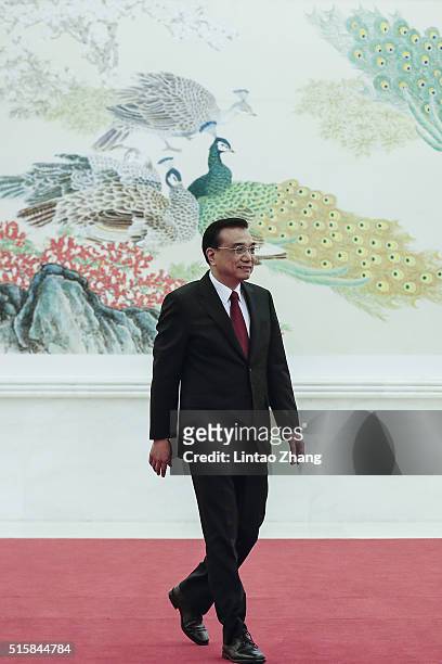 Chinese Premier Li Keqiang waves as he arrives a news conference following the closing session of the National People's Congress at the Great Hall of...