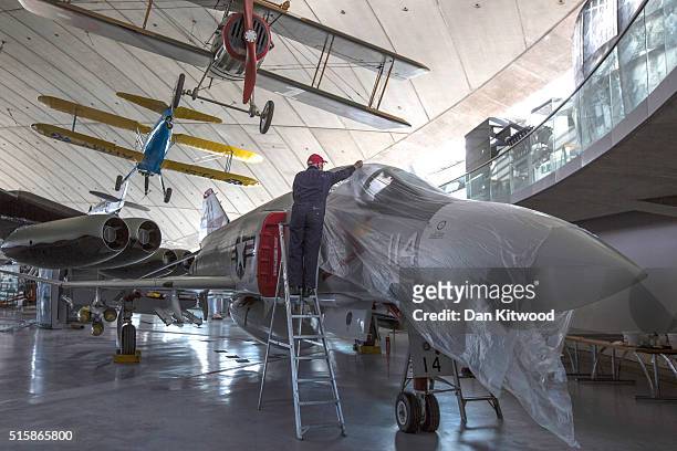Volunteer covers a F-4 after cleaning it inside the newly refurbished 'American Hanger' at the Imperial War Museum in Duxford on February 24, 2016 in...