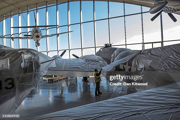 Volunteer helps cover a B-17 Flying Fortress after it was cleaned inside the newly refurbished 'American Hanger' on February 24, 2016 in Duxford,...