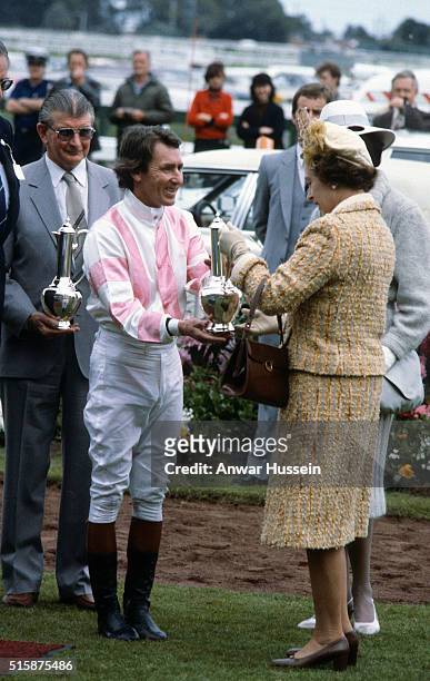 Queen Elizabeth ll presents a trophy when she attends the Melbourne Cup horse race during a tour of Australia on November 03, 1981 in Melbourne,...