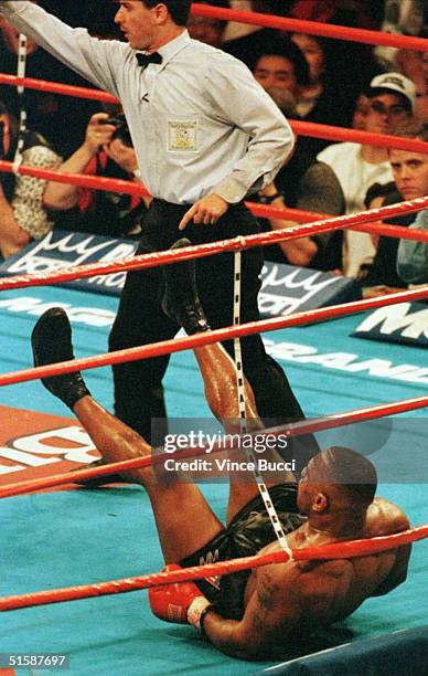 Heavyweight champion Mike Tyson is knocked down in the ring by challenger Evander Holyfield as referee Mitch Halpern orders Holyfield to a neutral...