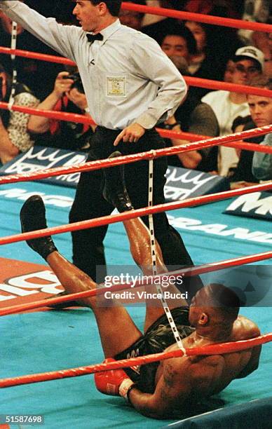 Heavyweight champion Mike Tyson is knocked down in the ring by challenger Evander Holyfield as referee Mitch Halpern orders Holyfield to a neutral...