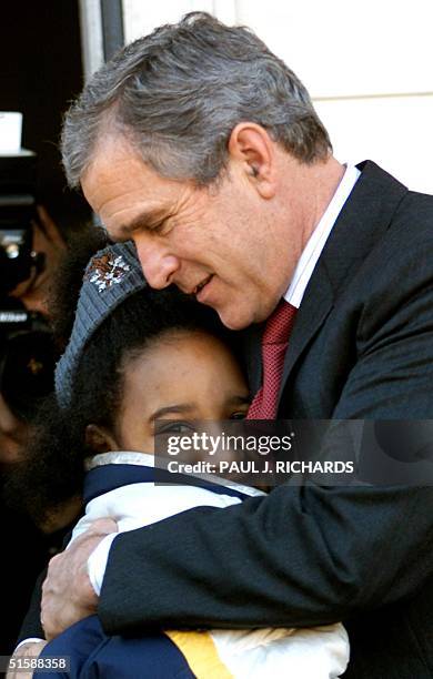 President George W. Bush hugs 9-year-old Kailah Johnson, an after school student who attends the faith-based Fishing school, which provides a safe...