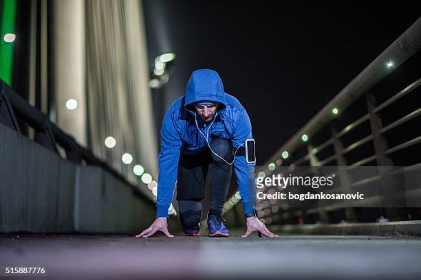jeune homme sportif en début position de vous préparer à courir - positionner photos et images de collection