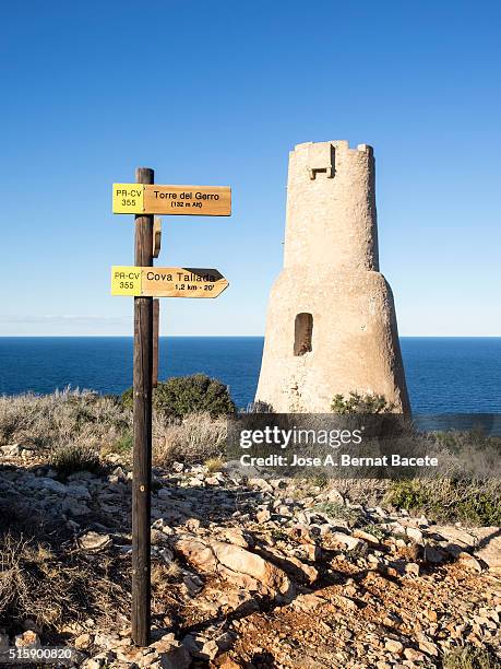 defensive tower of the 16th century on a cliff opposite to the sea and a signal with wooden arrows - gemengde signalen uitzenden stockfoto's en -beelden