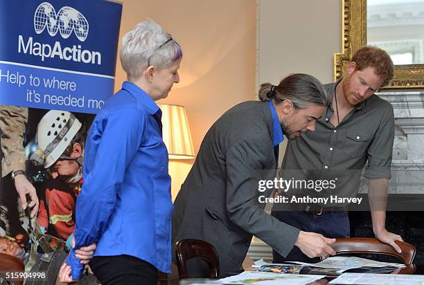 Prince Harry speaks with MapAction volunteer Kirsty Ferns and Hamish Pritchard during a briefing by MapAction to learn more about the charity's...