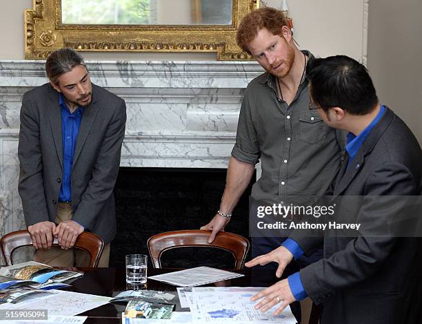 Prince Harry speaks with MapAction volunteers Hamish Pritchard and Wai-Ming Lee during a briefing by MapAction to learn more about the charity's...