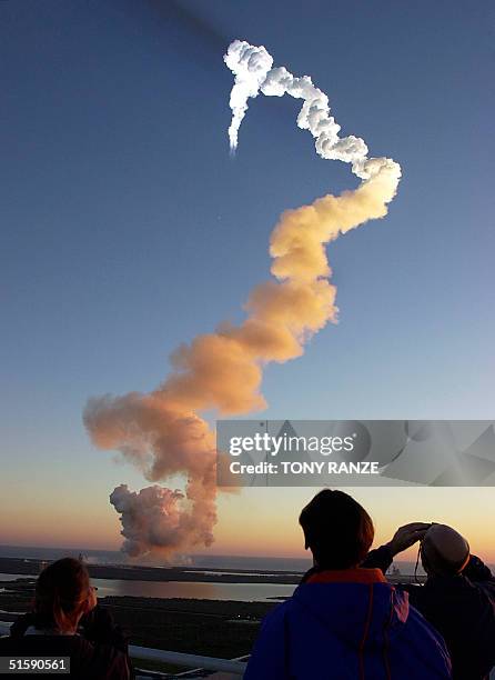 Workers view the launch of the space shuttle Discovery after blasting off launch pad 39-B at the Kennedy Space Center, FL. 08 March 2001. Discovery...