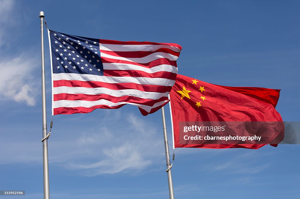 American Chinese windy day flags fly together on flagpole