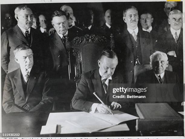 President Coolidge signing the Kellogg Peace Pact while Vice President Dawes and Secretary Kellogg look on.