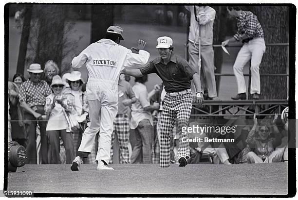Augusta, GA: Dave Stockton's caddie reaches out to slap Sttockton's hand after he sunk an eagle putt on the second hole 4/13. Stockton then birdied...