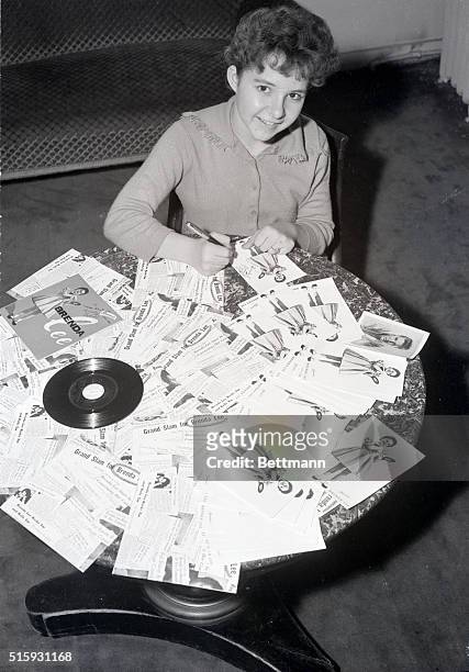 Paris, France: A little Miss with a big future, American singer Brenda Lee busily autographs photos of herself that she intends to send out to her...