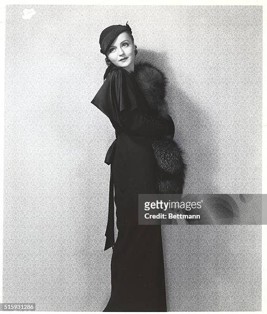 Fashion model Nancy Carroll wears a fur stole with a black dress and hat in the 1920s.