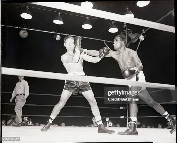 Jersey City, NJ: Welterweight champion Sugar Ray Robinson slips through Charley Fusari's guard and delivers a right to the jaw in their scheduled...