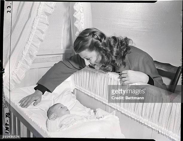Gstaad, Switzerland: Rita Hayworth, American movie star, seems lost in admiration of her baby daughter, Princess Yasmin, and the baby seems to be...