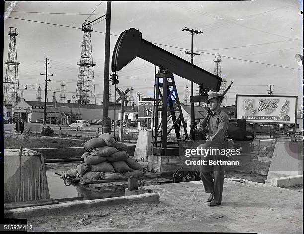 Los Angeles, CA: One of Uncle Sam's soldiers stands sentry duty near a sandbad protected oil well pump at an unnamed point in one of Southern...