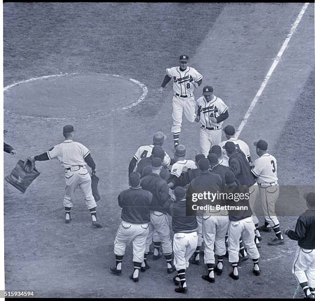 Milwaukee, WI: County Stadium- Eddie Mathews approaches home plate, which is loaded with players for the Milwaukee Braves, waiting to congratulate...